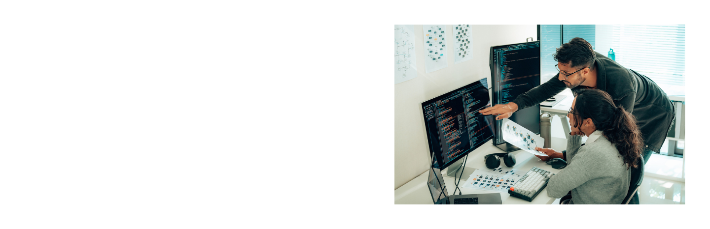 Two researchers collaborate at a workstation with multiple monitors displaying data in a modern office environment.